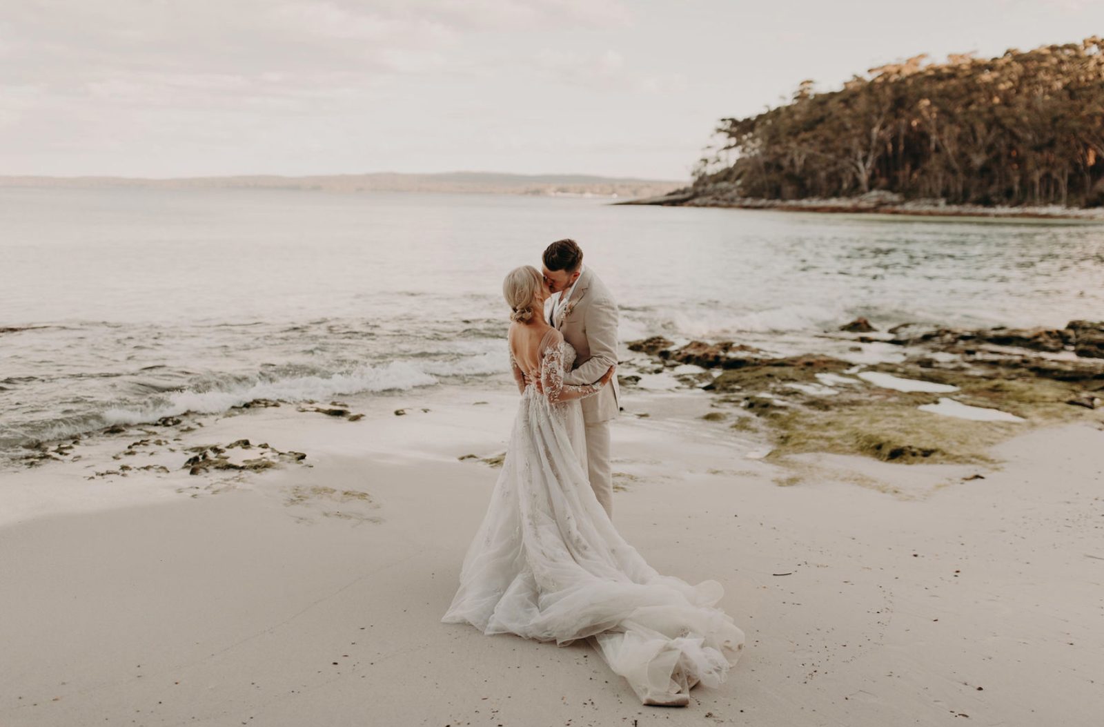 A couple embracing on a white-sand Jervis Bay beach
