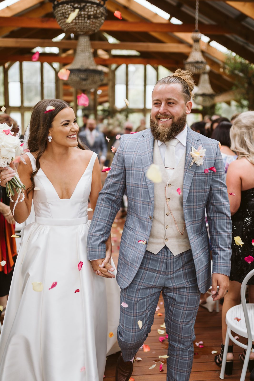 A bride and groom laughing through confetti as they walk back down the aisle