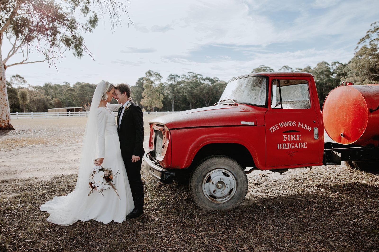 A bride and groom beside the farm&rsquo;s red fire truck